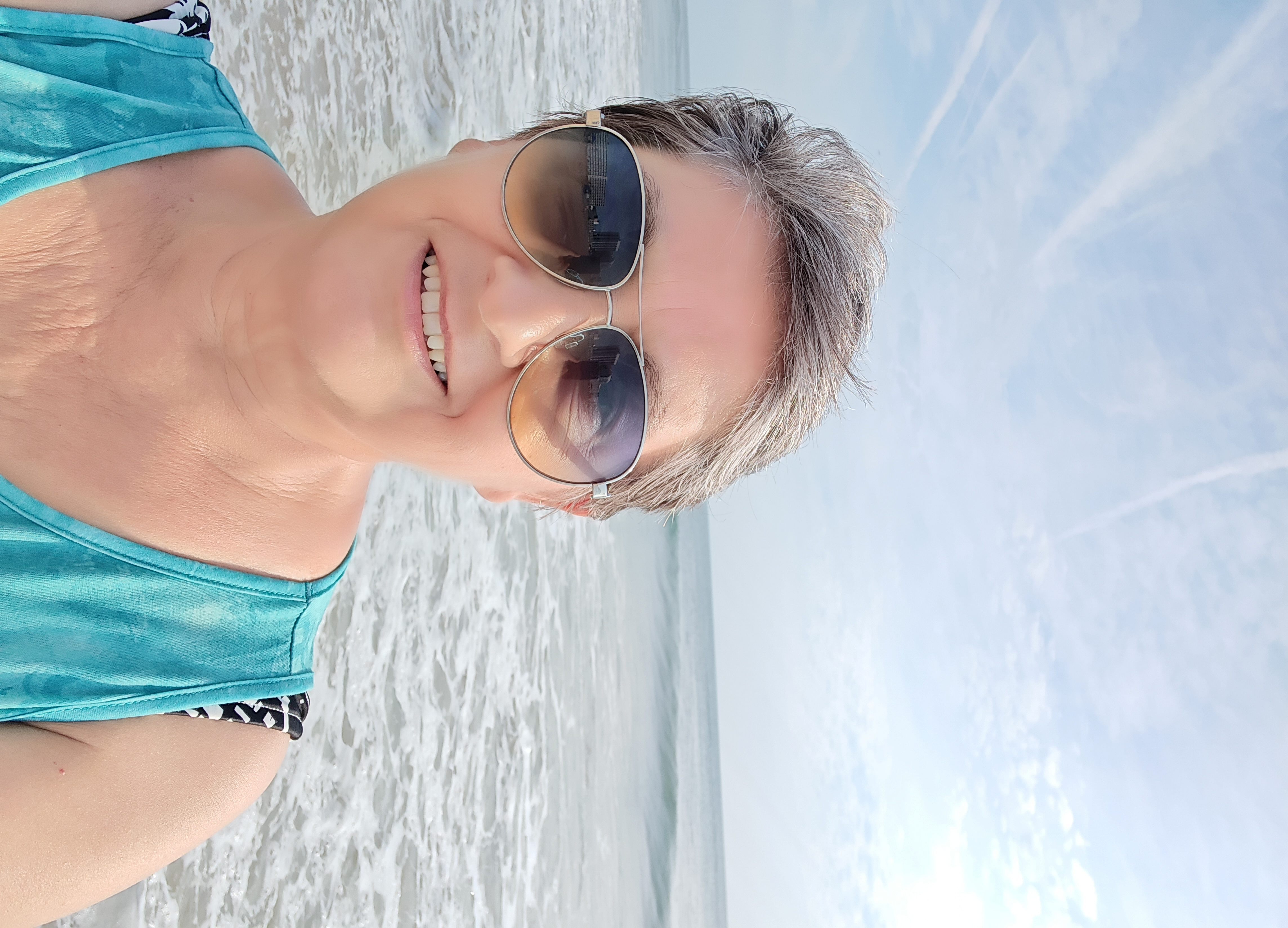 Sandy smiling on the beach on a bright, breezy day